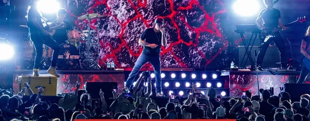 A band on the concert stage in front of a packed crowd at night