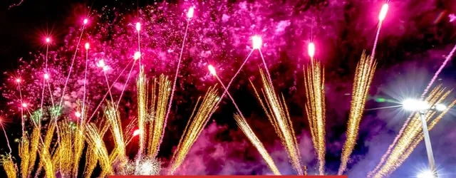 Pink and gold fireworks bursting over the venue at night