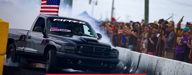 A Dodge Dakota smoking up Skid Row beside the crowd and a US flag